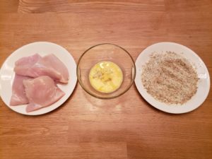 chicken on a plate, egg in a bowl, breading on a plate lined up in a row