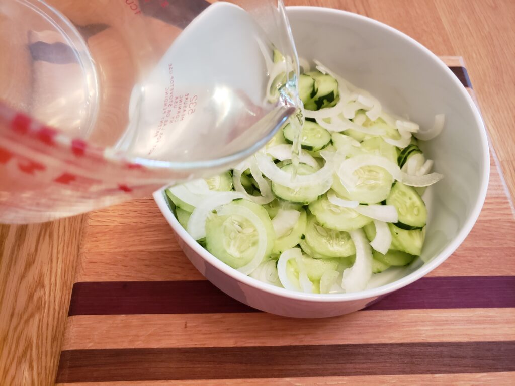 adding liquid to sliced cucumbers and onions