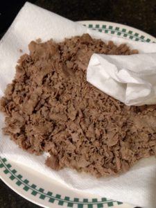 dabbing meat with paper towel to remove grease